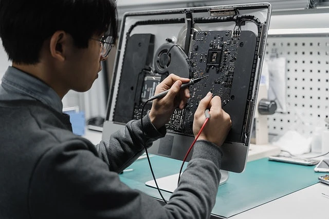 A computer repair technician fixing a Mac monitor